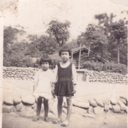 民國52年干城新村前的馬路,二個小女孩。馬路是泥沙,水溝還是石頭,背景是干城新村的房舍